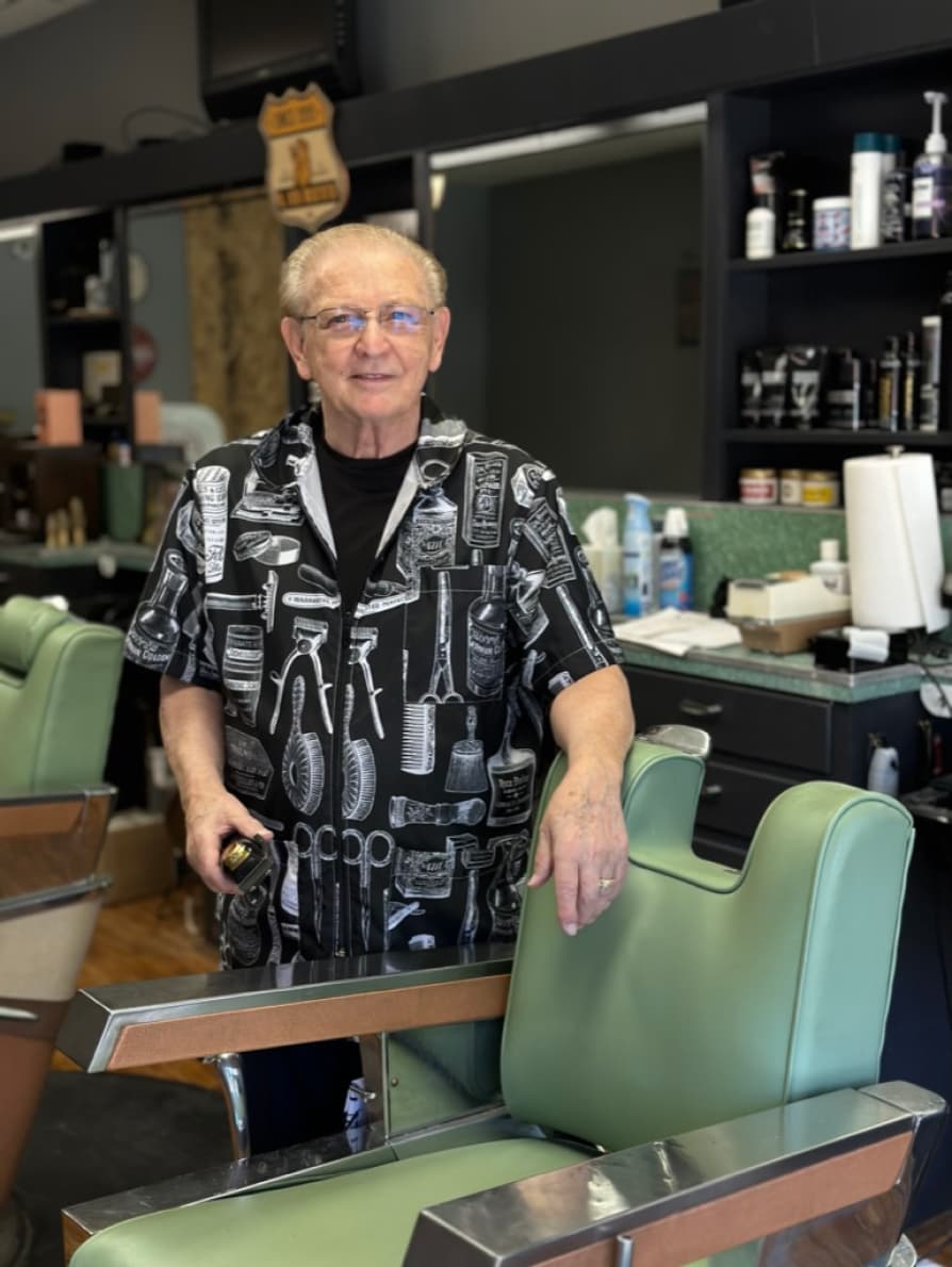 A photograph of Karl standing by the barber chair.